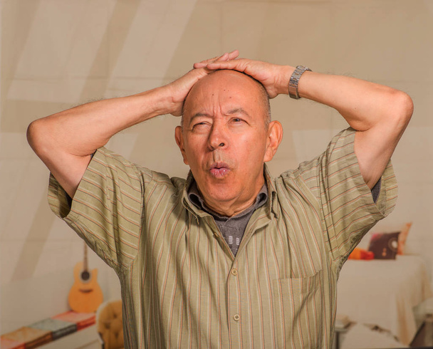 Retrato de un hombre maduro preocupado sosteniendo su cabeza con ambas manos, en un fondo borroso
 - Foto, Imagen