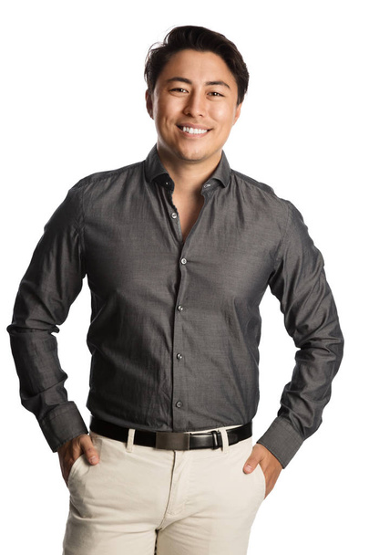 Красивый мужчина в серой рубашке стоит на белом фоне с широкой улыбкой на лице
. - Фото, изображение