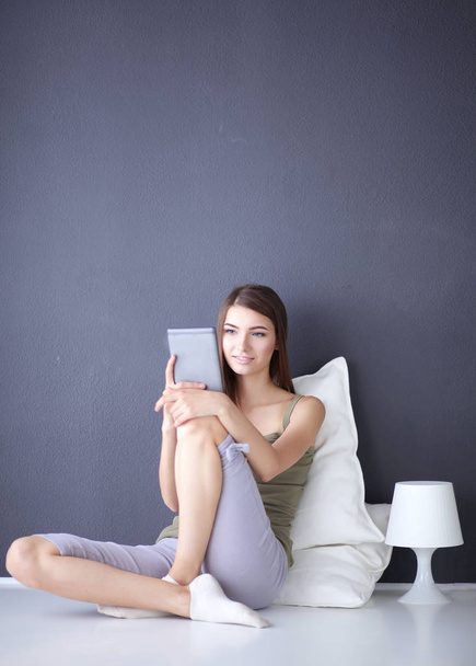 Pretty brunette woman sitting on the floor with a pillow and plane table - Fotografie, Obrázek