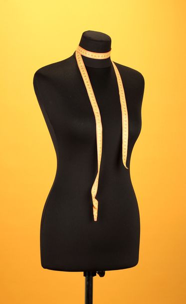 empty black mannequin with measuring tape on orange background - Fotó, kép