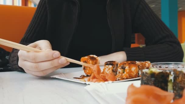 Kız suşi rulo yemek çubukları ile bir Japon restoranında yiyor. - Video, Çekim