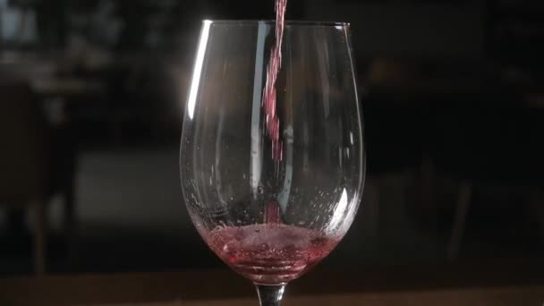 バーテンダーは、大きな透明な容器からガラスに赤ワインを注ぐ - 映像、動画