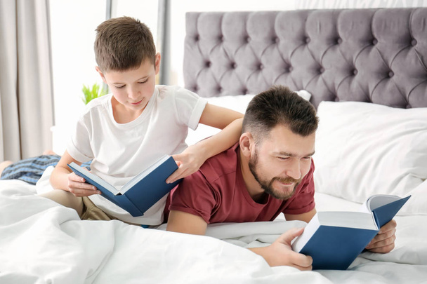 Little boy and his dad reading books in bedroom - Photo, Image