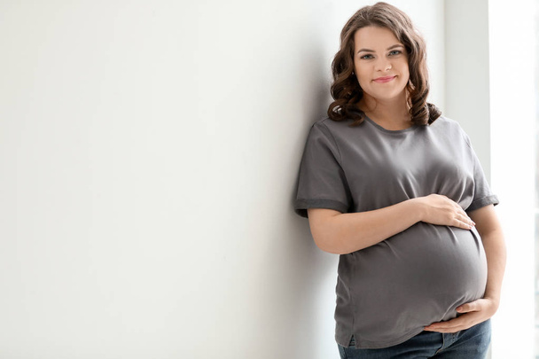 Young pregnant woman in casual clothes on light background - Φωτογραφία, εικόνα