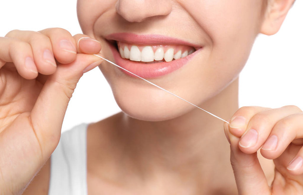 Młoda kobieta nicią dentystyczną zęby na białym tle, zbliżenie - Zdjęcie, obraz