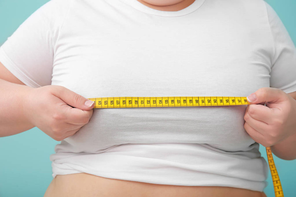 Overweight woman with measuring tape on color background - Photo, image