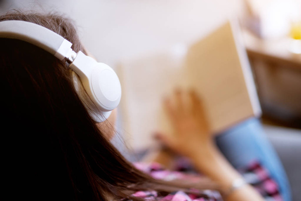 young beautiful woman sitting and reading book while listening to music on headphones - Фото, зображення