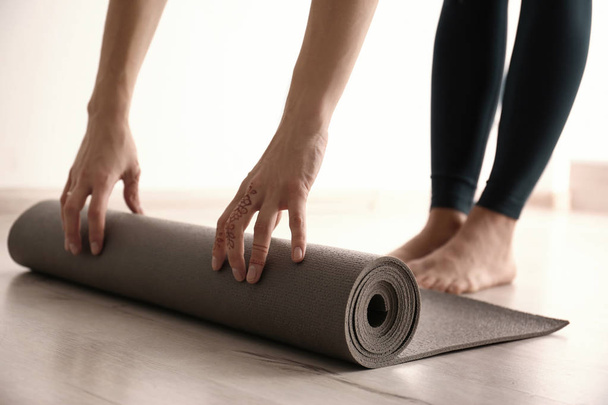 Young woman with yoga mat indoors, closeup - Фото, изображение