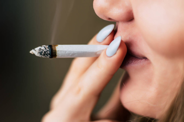 Cannabiskraut, einen Joint in der Hand, den eine Frau raucht. Rauch auf schwarzem Hintergrund. Konzepte des medizinischen Marihuana-Konsums und der Legalisierung von Cannabis. - Foto, Bild