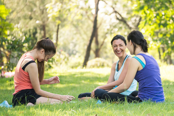 Activiteiten in de familie, moeder en dochter ontspannen in het park na het beoefenen van yoga. - Foto, afbeelding