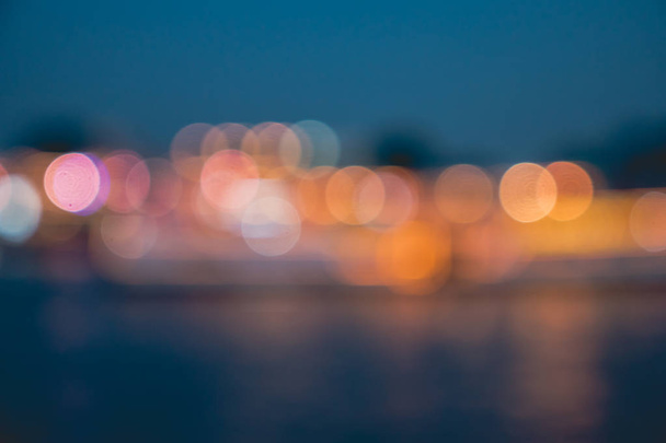Luces borrosas de la ciudad con efecto bokeh reflejado en el agua
 - Foto, Imagen