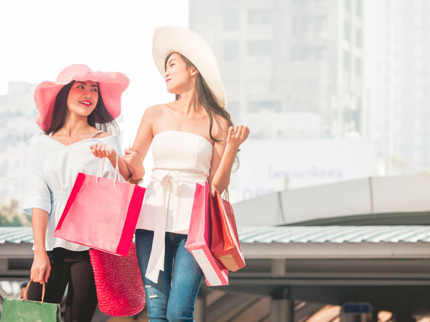 Mujeres jóvenes felices con bolsas de compras disfrutando en las compras, chicas asiáticas se están divirtiendo con sus compras en la ciudad. Concepto de consumo y estilo de vida
 - Foto, imagen