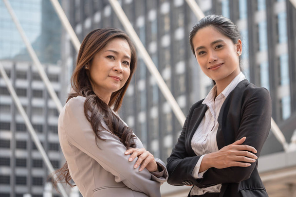 Dos mujeres de negocios asiáticas sonriendo con fondo de escena urbana. Trabajo en equipo y concepto de éxito
 - Foto, Imagen