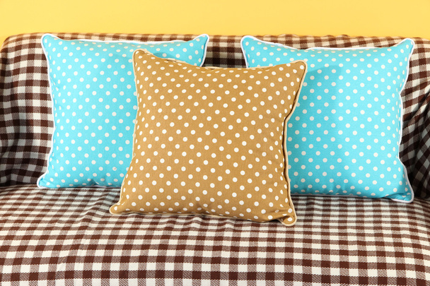 Colorful pillows on couch on yellow background - Φωτογραφία, εικόνα