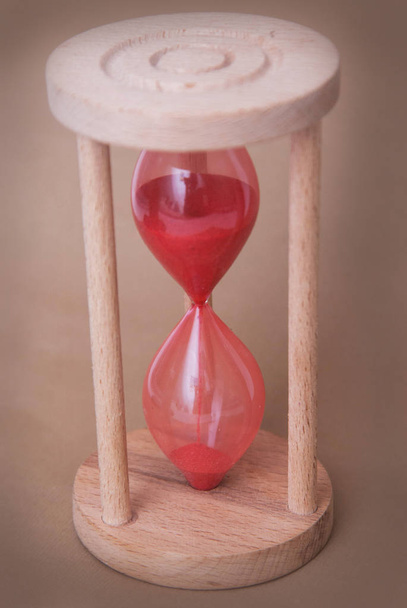 Červená přesýpací hodiny jako čas předání konceptu a málo času. Přesýpací hodiny. Neutrální slonoviny pozadí. Vertikální obrázek. - Fotografie, Obrázek