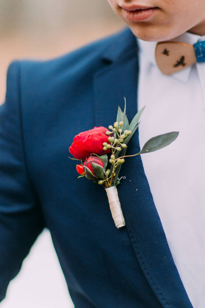 Red boutonniere in the grooms jacket close up - Foto, Bild