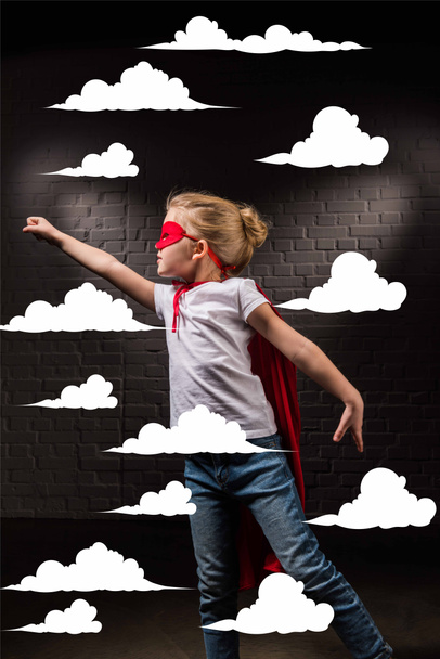 női gyermek repül a piros szuperhős maszk, és repül a felhők - Fotó, kép