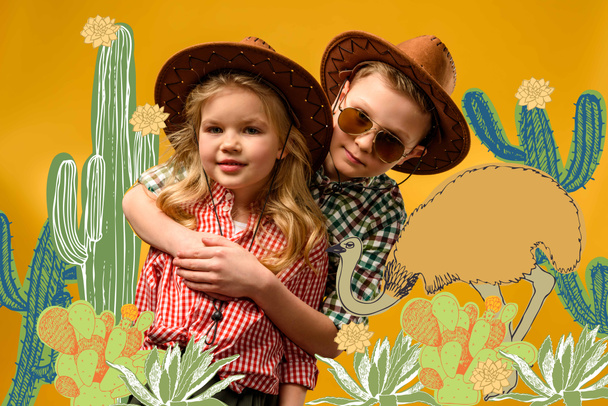 little stylish travelers in hats hugging, on yellow with cactuses and ostrich illustration - 写真・画像