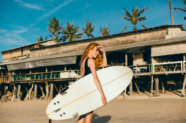 Szörfös lány séta-a Tanács-a homokos strandon. Szörfös lány. Gyönyörű fiatal nő a tengerparton. vízi sportok. Egészséges aktív életmód. Szörfözés. Nyári vakáció. Extrém Sport. Bali - Fotó, kép