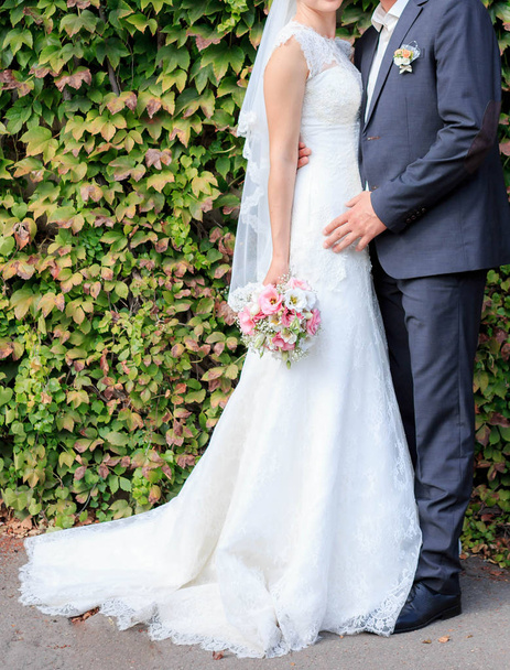 Nevěsta a ženich stojí poblíž zelená stěna - Fotografie, Obrázek