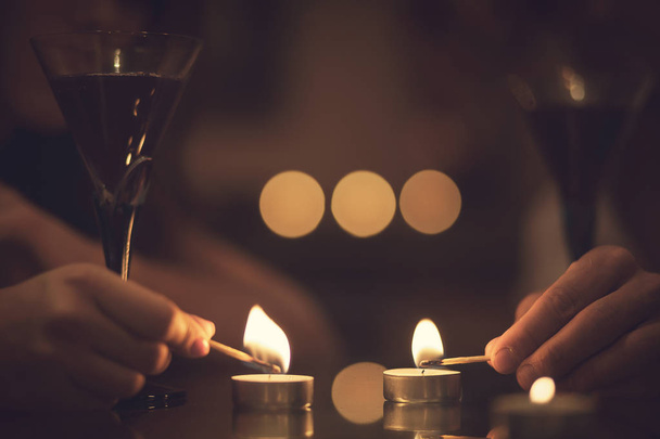 ロマンチックな雰囲気。キャンドル、赤ワインのグラスと 2 つの手. - 写真・画像