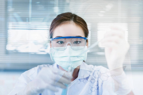 Női tudós vagy orvos, zöld megoldás a laboratórium - Stock Fotó egy nő orvos vagy látszó-on egy kémcsőbe, zöld oldatot egy laboratóriumban orvosszakértő. - Fotó, kép