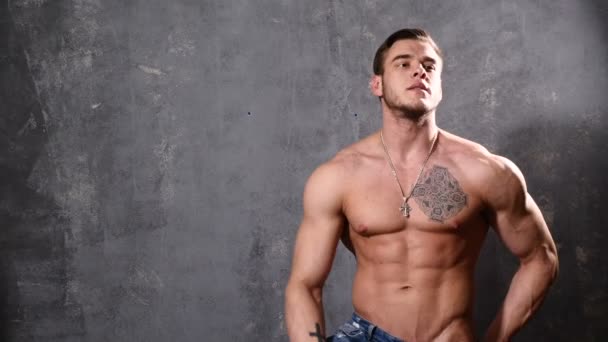 bodybuilder uomo forte e muscolare. Uomo in posa su uno sfondo nero, mostra i suoi muscoli. bellissimi muscoli addominali e toracici
. - Filmati, video