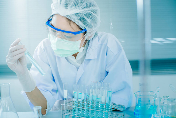 Ασιατικές γυναίκες επιστήμονας με δοκιμαστικό σωλήνα κάνοντας έρευνα στο κλινικό εργαστήριο. Επιστήμη, χημεία, τεχνολογία, βιολογία και άνθρωποι έννοια - Φωτογραφία, εικόνα