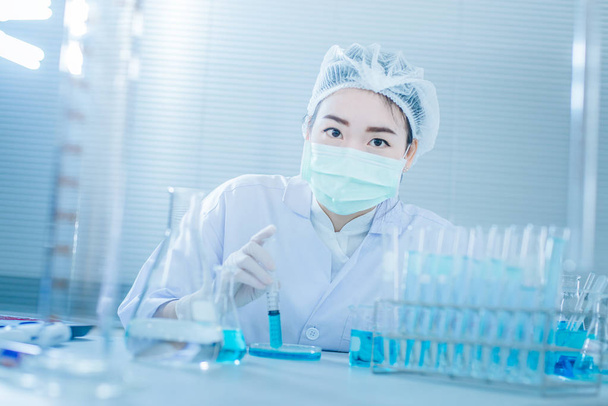 Científica asiática con tubo de ensayo investigando en laboratorio clínico.Concepto de ciencia, química, tecnología, biología y personas
 - Foto, Imagen