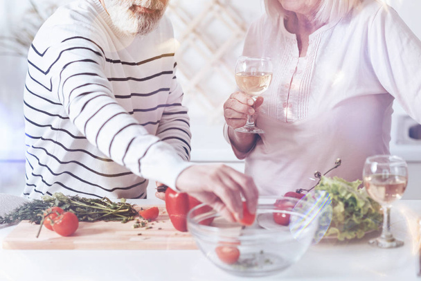 So tasty. Pleasant loving aged couple standing in the kitchen and cooking while making vegetable salad - Fotografie, Obrázek