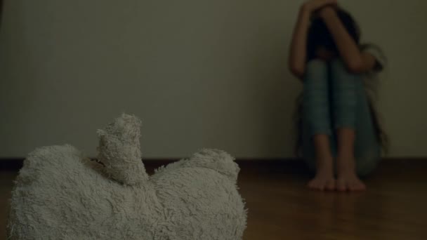uma criança desesperada em depressão senta-se na parede de seu quarto, tenta tentar suicídio. ao lado dele é um brinquedo macio abandonado. 4k, câmera lenta
. - Filmagem, Vídeo