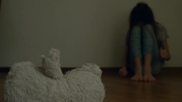 うつ病の絶望的な子は、自殺しようとする彼の部屋の壁に座っています。隣には、放棄された柔らかいおもちゃです。4 k、スローモーション. - 映像、動画