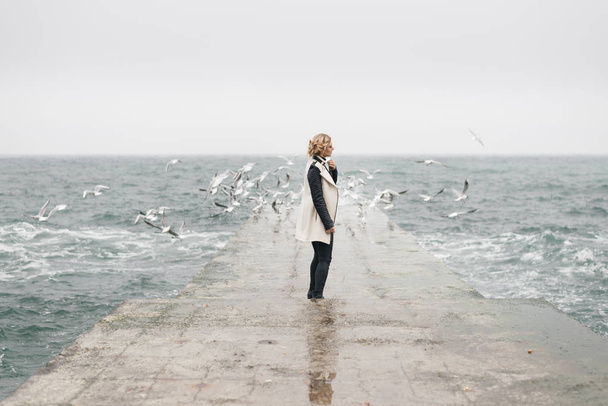 Молода жінка стоїть у профілі на вологому з хвиль пірсу
. - Фото, зображення