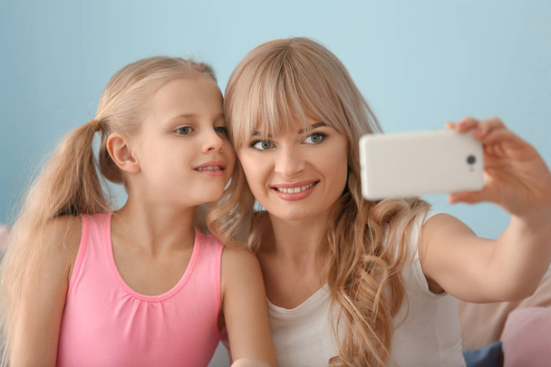 Cute little girl and her mother taking selfie at home - Zdjęcie, obraz