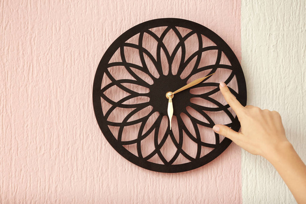 Female hand pointing on clock hanging on wall. Time management concept - Фото, изображение