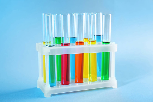Test tubes with colorful liquids in holder on color background - Foto, Imagen