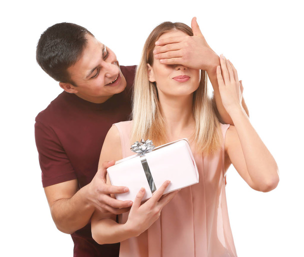 Young man giving present to his beloved girlfriend on white background - Foto, immagini
