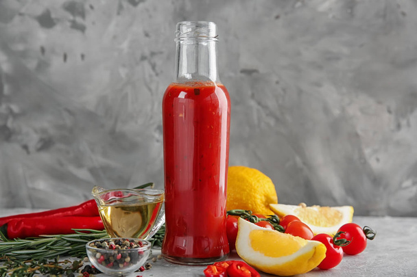 Bottiglia con gustosa salsa di pomodoro, verdure e condimenti in tavola
 - Foto, immagini