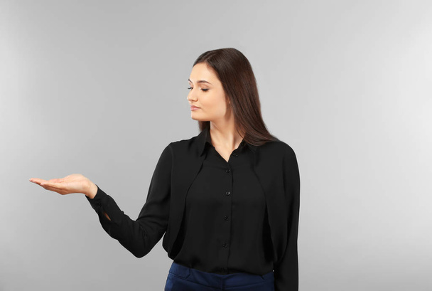 Young businesswoman holding something on gray background - Fotó, kép
