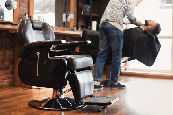 Chaise et coiffeur professionnel travaillant avec le client dans un salon de coiffure moderne
 - Photo, image