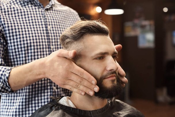 Barbeiro profissional trabalhando com o cliente no salão de cabeleireiro
 - Foto, Imagem