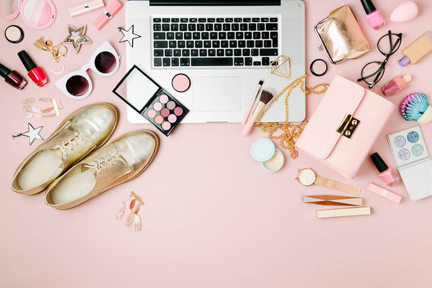 Fashion blogger workspace with laptop and female accessories, cosmetics products on pale pink table. - Zdjęcie, obraz