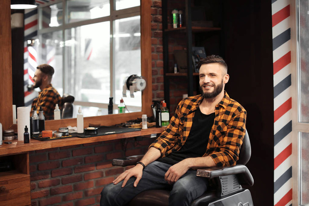 Handsome man with trendy hairstyle in barbershop - Photo, Image