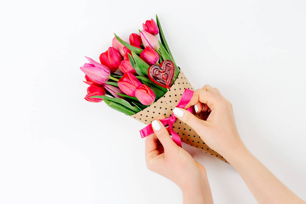 Closeup of female hands holding bouquet with pink and red tulips isolated on white background - Photo, image