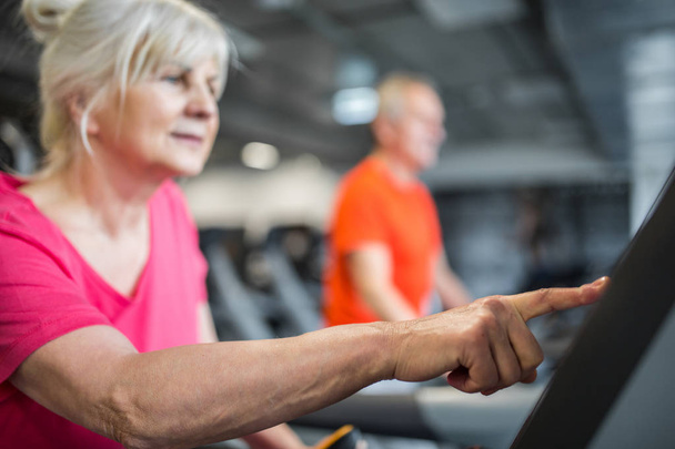 Senior lady touching screen of treadmill at gym - Foto, Bild