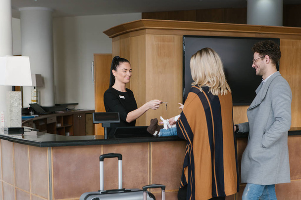 Receptie werknemer geeft de sleutel aan familie bij hotel - Foto, afbeelding