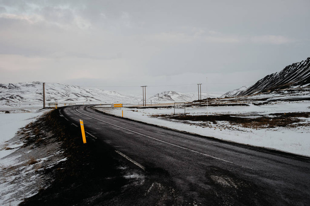 Uma estrada ventosa na Islândia que conduz através de uma paisagem nevada
 - Foto, Imagem