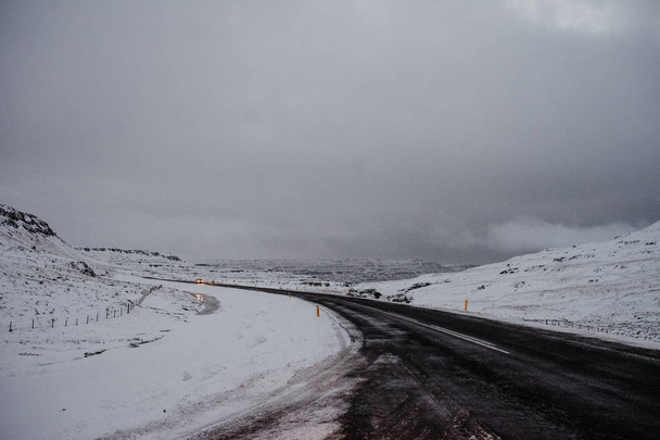 Μια θυελλώδη δρόμο στην Ισλανδία, που οδηγούν μέσα από ένα ορεινό πλάτωμα εντελώς καλυμμένο με χιόνι - Φωτογραφία, εικόνα