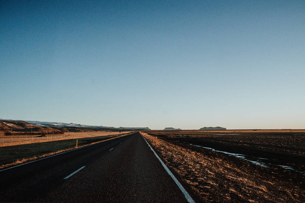 Rovná silnice vedoucí směrem k některé hory Islandu při západu slunce - Fotografie, Obrázek