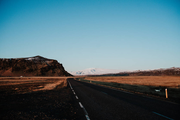 A straight road leading towards some mountains in Iceland at sunset - Fotó, kép